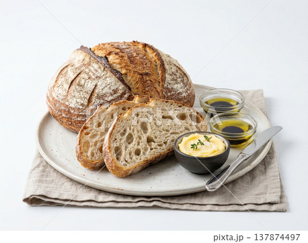 Artisan sourdough bread slices with butter, olive oil, and balsamic vinegar on a rustic plate with linen napkin, baked goods 137874497