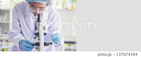 Banner Asian woman scientist hand write note research in medical lab look at science microscope. Panorama biology chemistry lab. Asian Female technician laboratory using microscope with copy space Banner Asian woman scientist hand write note research in medical lab look at science microscope. Panorama biology chemistry lab. Asian Female technician laboratory using microscope with copy space 137874584