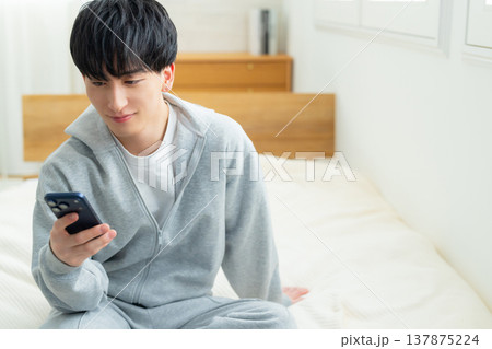 ベッドでスマホを見る男性 ベッドでスマホを見る男性 137875224