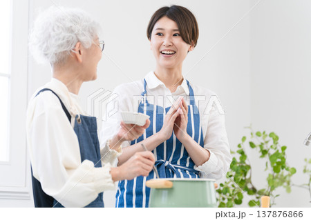 キッチンに立つ若い女性とシニア女性　料理イメージ 137876866