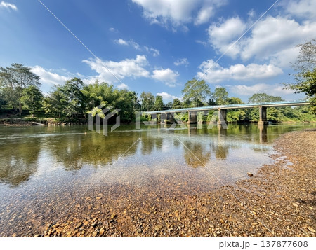 Scenic River Landscape with Concrete Bridge under Clear Blue Sky and Lush Greenery Scenic River Landscape with Concrete Bridge under Clear Blue Sky and Lush Greenery 137877608