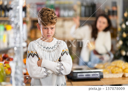 Sad boy while shopping with mother at grocery store on New Years Eve. 137878009