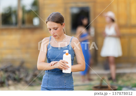 Young woman applying sunscreen outside country house 137878012