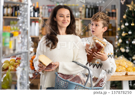 Adult woman with son choosing products in grocery store Adult woman with son choosing products in grocery store 137878250