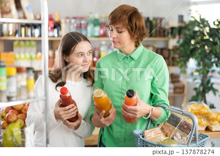 Mother and daughter choose tasty juice together in grocery section of supermarket 137878274