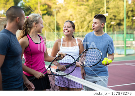 Four tennis players standing on court and talking about match Four tennis players standing on court and talking about match 137878279