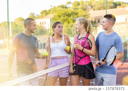 Men and women having conversation on outdoor tennis court Men and women having conversation on outdoor tennis court 137878371
