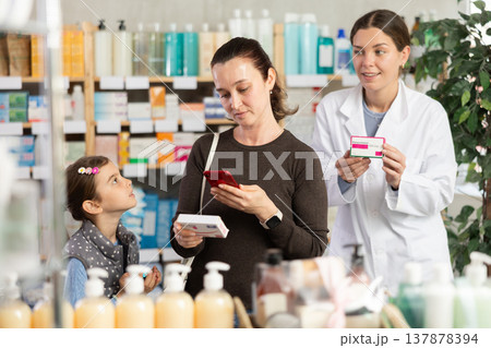 Concerned woman checking medicine safety online at pharmacy Concerned woman checking medicine safety online at pharmacy 137878394