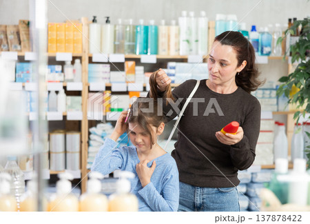 Adult woman chooses shampoo for daughter with lice 137878422