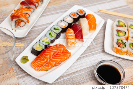 Variations of sashimi and sushi with soy sauce on table 137878474