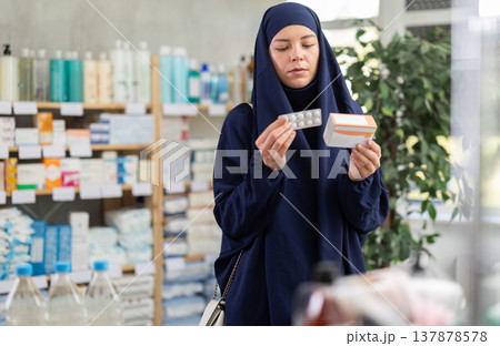 Young Muslim woman customer choosing pills in box in drugstore 137878578