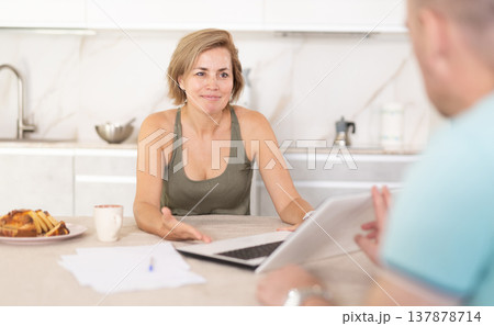 Positive middle-aged woman manager talking to colleague in the kitchen Positive middle-aged woman manager talking to colleague in the kitchen 137878714