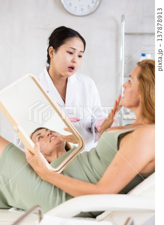 Professional cosmetologist talking about anti-aging skincare to patient 137878913