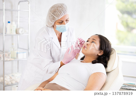 Middle-aged doctor giving injection in face 137878919