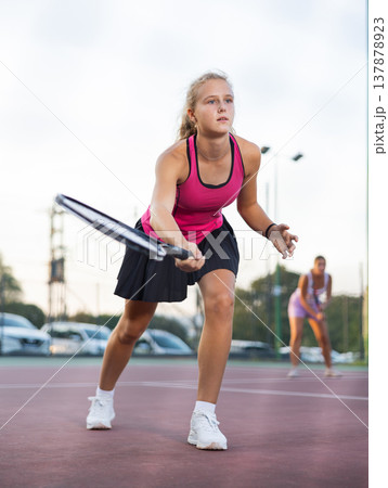 Young forcefully teenage girl playing tennis close to net on court Young forcefully teenage girl playing tennis close to net on court 137878923
