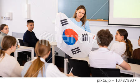 Adult female teacher showing South Korea flag to students Adult female teacher showing South Korea flag to students 137878937