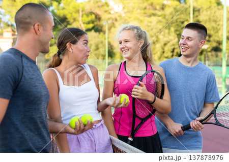 Four smiling sportsmens men and women with rackets emotionally talking and laughing Four smiling sportsmens men and women with rackets emotionally talking and laughing 137878976