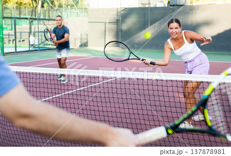 Sporty woman plays tennis on court. View through tennis net Sporty woman plays tennis on court. View through tennis net 137878981
