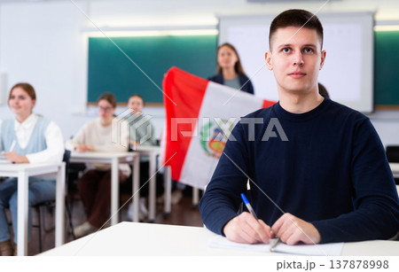 Teenage students in class and listening carefully to female teacher holding Peru flag in hands 137878998