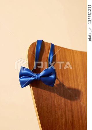 Blue bow tie chair wooden back in warm studio light with soft shadow subtle texture 137881211