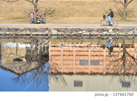 江戸川区を流れる旧中川に映り込む自転車乗る人と家並み 江戸川区を流れる旧中川に映り込む自転車乗る人と家並み 137881780