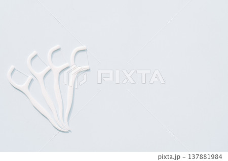 Group of white dental floss picks on light blue background with large copy space, dental care concept 137881984