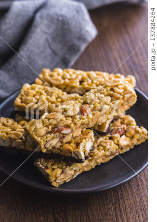 Stacked Peanut Bars With Chocolate Coating on Black Plate Rustic Snack Close-Up 137884264