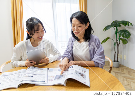 カタログを見る母娘 137884402