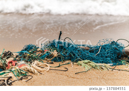 Discarded fishing nets and tangled ropes lying on sandy beach near ocean waves Koh Samui Thailand Discarded fishing nets and tangled ropes lying on sandy beach near ocean waves Koh Samui Thailand 137884551
