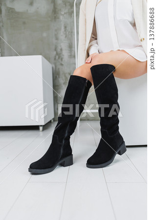 Close-up of female legs in black tall leather suede boots. Women's winter shoes. Warm women's boots. Women's modern shoes 137886688