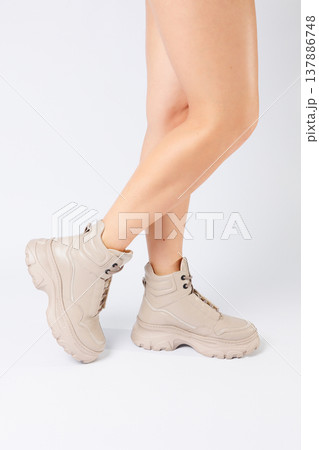 Female legs in beige leather shoes from the new collection on a white background female legs in fashionable shoes made of eco-leather spring 2022. 137886748