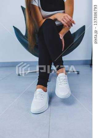 Women's legs close-up in white leather sneakers made from natural leather.Collection of women's summer shoes Women's legs close-up in white leather sneakers made from natural leather.Collection of women's summer shoes 137886793