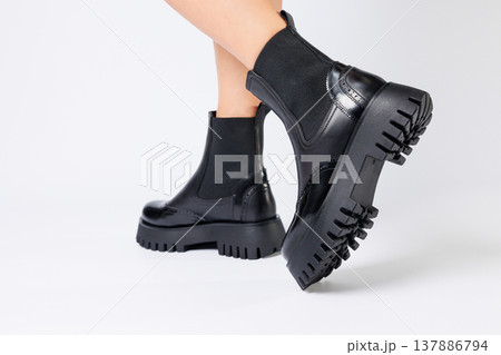 New collection of women's shoes spring 2022. girl's legs in new shoes. Legs in black boots. Low running boots made of genuine leather New collection of women's shoes spring 2022. girl's legs in new shoes. Legs in black boots. Low running boots made of genuine leather 137886794