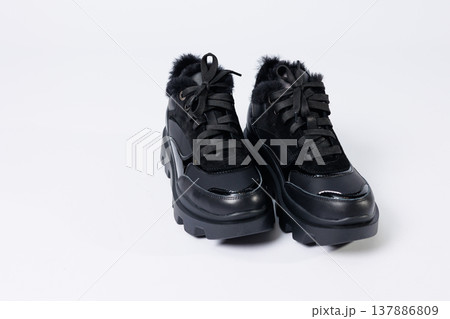 Women's fashionable black leather sneakers with fur on a white background. New collection of women's winter sneakers 2022 Women's fashionable black leather sneakers with fur on a white background. New collection of women's winter sneakers 2022 137886809