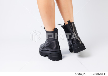 Woman in trendy black shoes on a white background, close-up. Woman's legs in stylish leather shoes 137886811