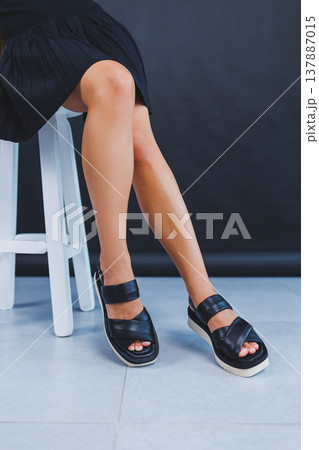 Women's legs close-up in black leather sandals made of genuine leather.Collection of women's summer shoes 137887015