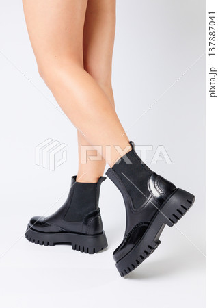 New collection of women's shoes spring 2022. girl's legs in new shoes. Legs in black boots. Low running boots made of genuine leather 137887041