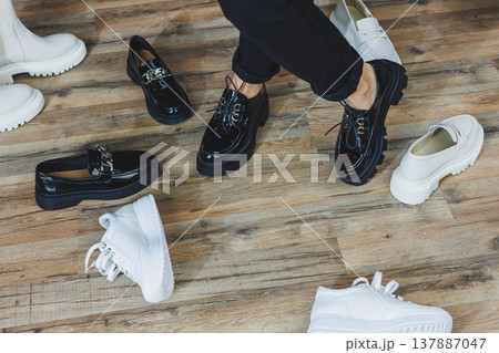 A woman chooses shoes against a brick wall. Several pairs of women's leather shoes 137887047
