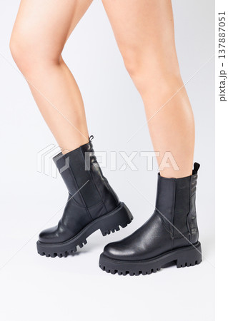 Women's black spring boots made of genuine leather are dressed on bare feet Women's black spring boots made of genuine leather are dressed on bare feet 137887051