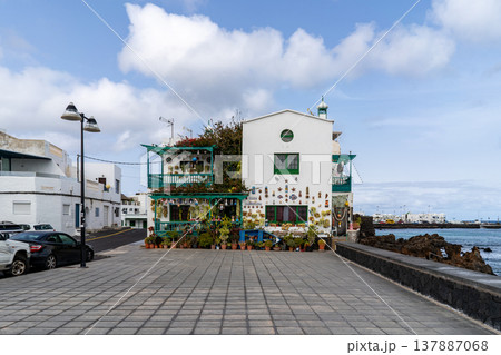 A charming building in Punta Mujeres, Lanzarote, decorated with plants and ornaments, stands by the sea under a cloudy sky. A charming building in Punta Mujeres, Lanzarote, decorated with plants and ornaments, stands by the sea under a cloudy sky. 137887068