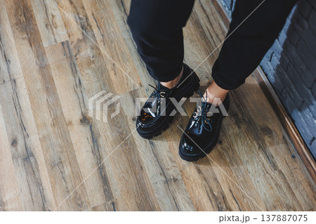 Beautiful woman with legs in fashionable clothes, stylish leather black patent leather lace-up shoes close-up. Women's image in spring style 137887075