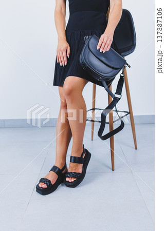 Women's legs close-up in black leather sandals made of genuine leather.Collection of women's summer shoes Women's legs close-up in black leather sandals made of genuine leather.Collection of women's summer shoes 137887106