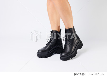 Woman in trendy black shoes on a white background, close-up. Woman's legs in stylish leather shoes Woman in trendy black shoes on a white background, close-up. Woman's legs in stylish leather shoes 137887107