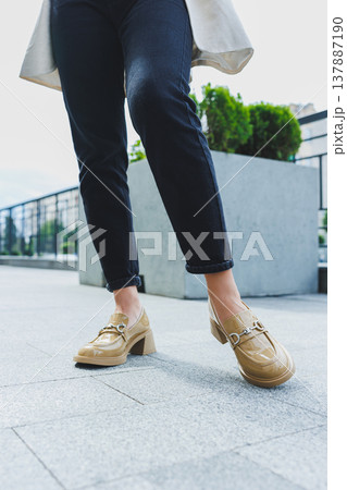Female legs in black jeans and beige high heels. Beige leather shoes close-up Female legs in black jeans and beige high heels. Beige leather shoes close-up 137887190
