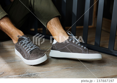 Male legs in gray casual sneakers. Comfortable men's summer shoes. Male legs in gray casual sneakers. Comfortable men's summer shoes. 137887197