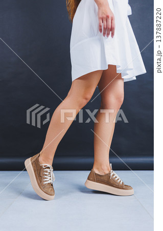 Women's brown leather sneakers on the legs close-up. Collection of summer women's shoes 137887220