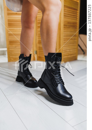 Beautiful female legs in black leather boots. New collection of women's winter shoes. Beautiful female legs in black leather boots. New collection of women's winter shoes. 137887225