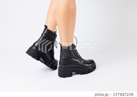Woman in trendy black shoes on a white background, close-up. Woman's legs in stylish leather shoes Woman in trendy black shoes on a white background, close-up. Woman's legs in stylish leather shoes 137887226