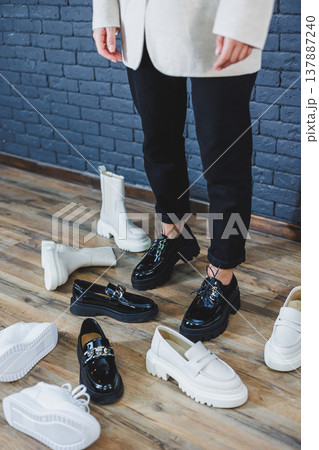 A woman chooses shoes against a brick wall. Several pairs of women's leather shoes 137887240