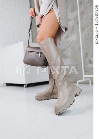Close-up of female legs in beige leather boots. Women's winter shoes. Warm women's boots 137887256